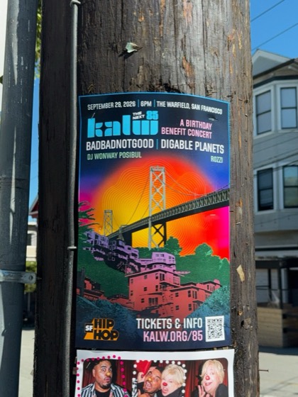 A poster for KALW The Next 85 at The Warfield, photographed on a wooden telephone pole